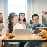 Un groupe diversifié de professionnels engagés dans une séance de brainstorming autour d'une table en bois avec la technologie présente.
