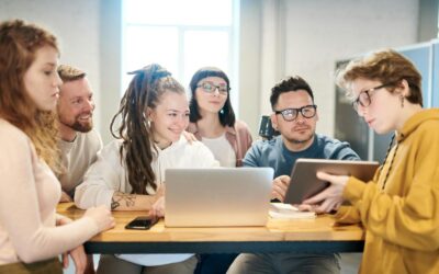 Un groupe diversifié de professionnels engagés dans une séance de brainstorming autour d'une table en bois avec la technologie présente.