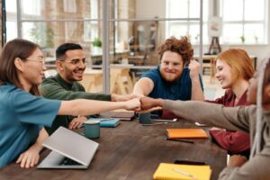 Un groupe diversifié de jeunes professionnels partageant un poing levé lors d'une réunion collaborative.
