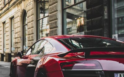 Voiture de sport rouge élégante garée dans une charmante rue historique de Prague, mettant en valeur l'élégance urbaine et le design puissant.