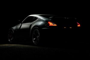 Une photo spectaculaire d'une voiture de sport Nissan 370Z illuminée dans l'obscurité par des feux arrière vibrants.