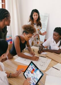 Groupe de femmes collaborant sur un projet créatif dans un environnement de bureau moderne.