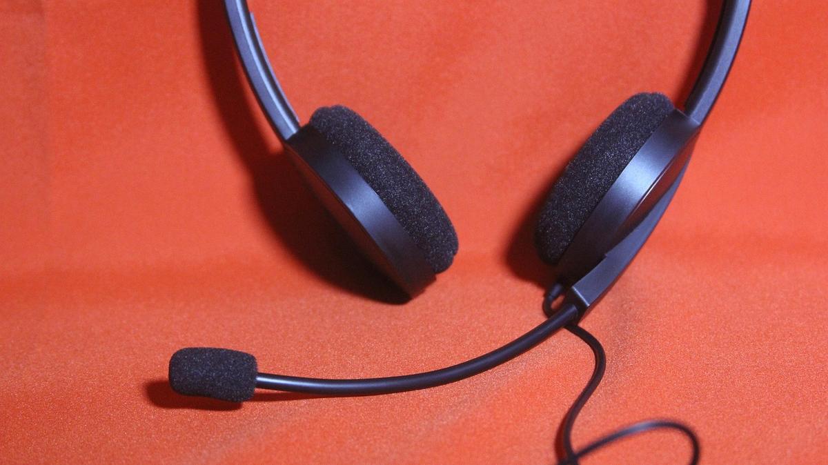 Casque audio noir avec micro réglable sur fond rouge