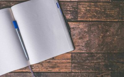 Un cahier ligné ouvert avec un stylo bleu sur du bois rustique