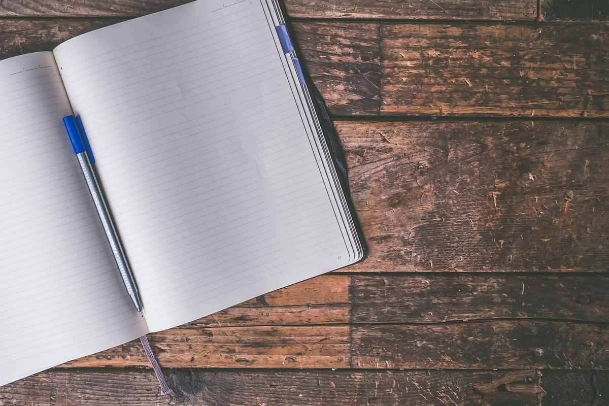 Un cahier ligné ouvert avec un stylo bleu sur du bois rustique