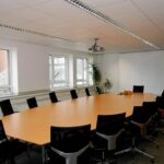 Salle de réunion moderne avec table ovale, chaises, fenêtres et tableau blanc