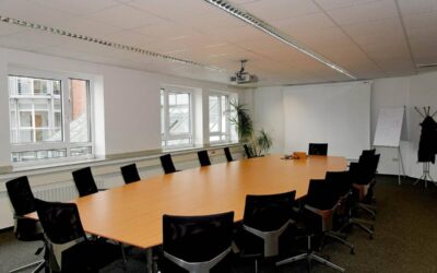 Salle de réunion moderne avec table ovale, chaises, fenêtres et tableau blanc
