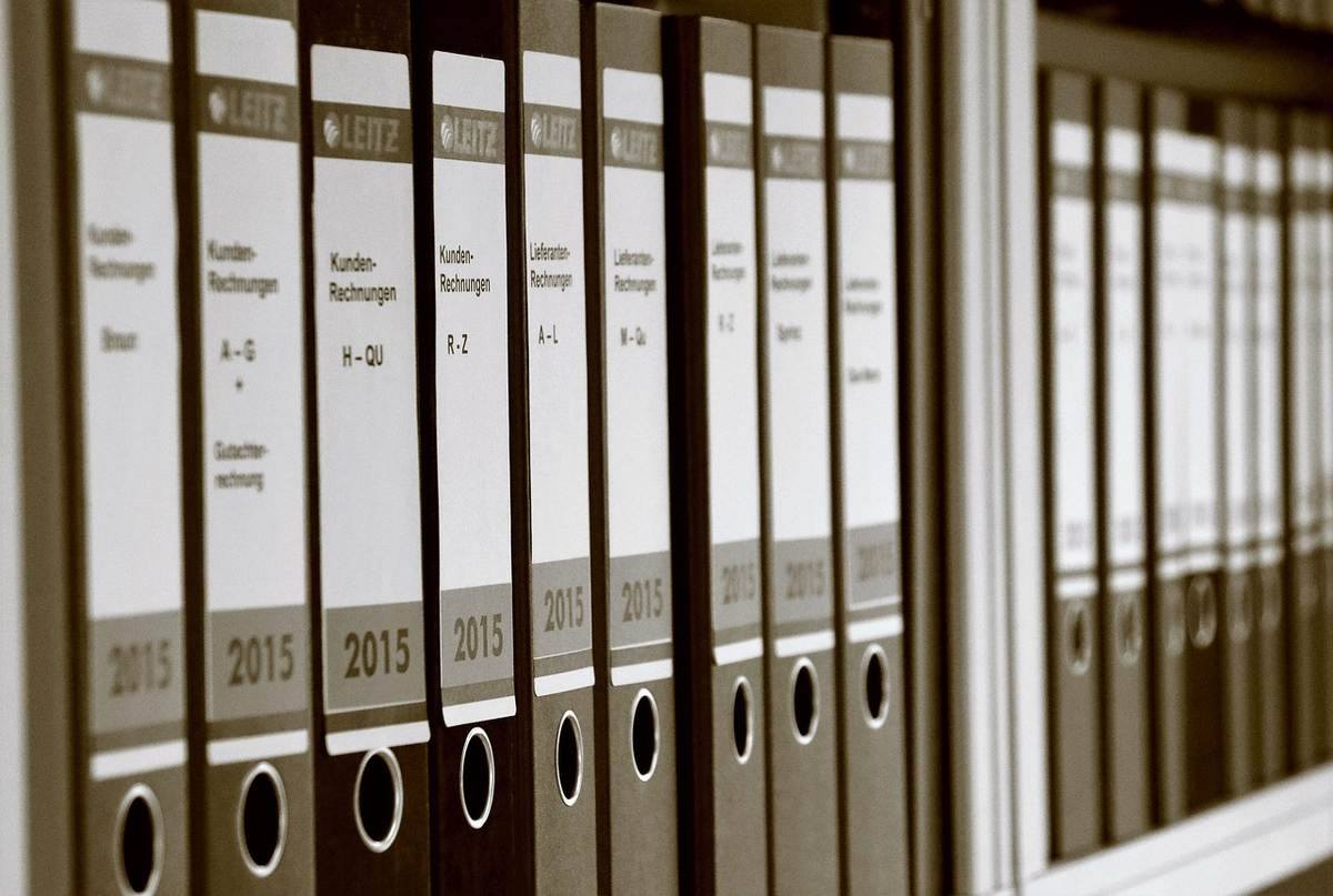 Dossiers archivés avec étiquettes et anneaux sur une étagère de bureau