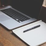 Un ordinateur portable, un cahier vierge et un stylo sur du bois
