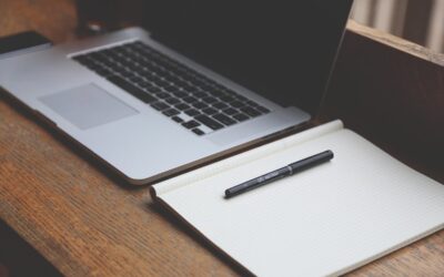 Un ordinateur portable, un cahier vierge et un stylo sur du bois