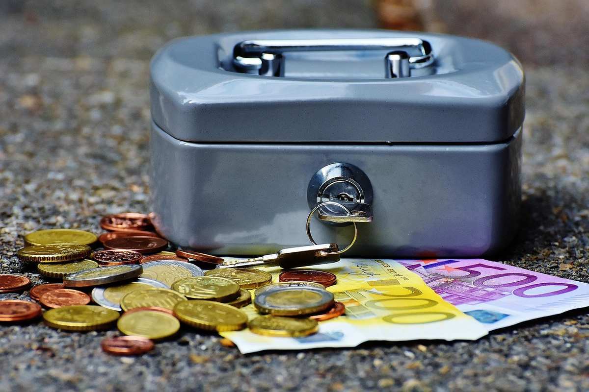 Boîte à argent avec pièces et billets sur le sol